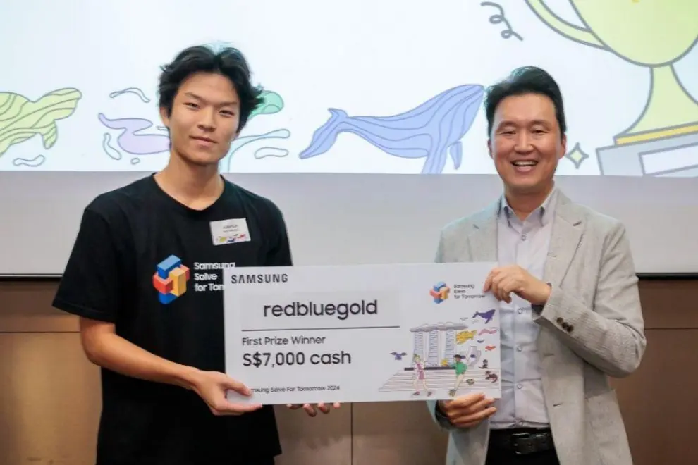 Team redbluegold's Aiden Lim (left), receiving the prize from Dennis Jang, President, Samsung Electronics Singapore (right), as the grand winner of Samsung Solve for Tomorrow 2024 in Singapore